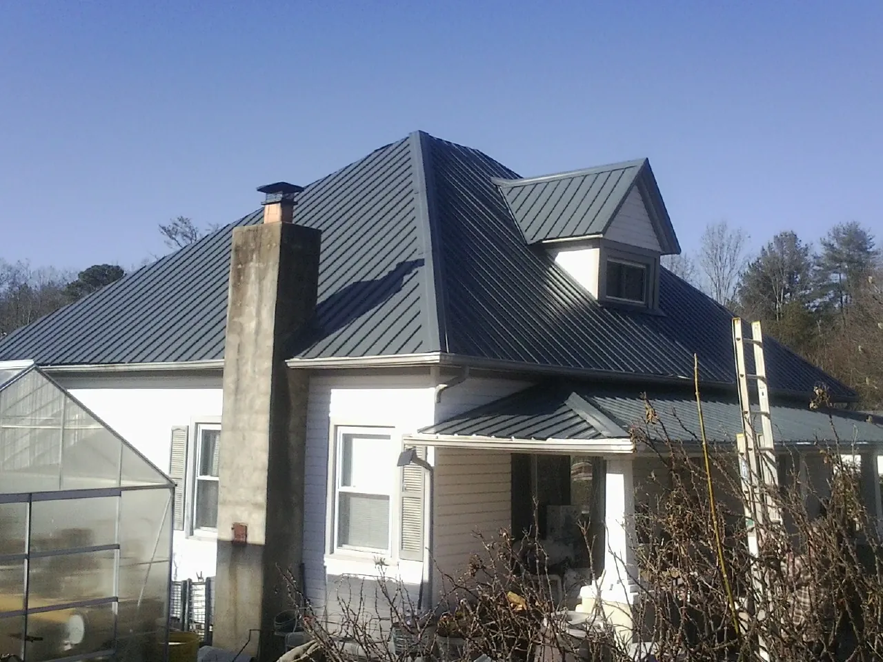 Dark blue standing seam metal roof on a white farmhouse with dormer — Slate & Tile Roof Repair by Roofing Brothers in Ottawa Lake