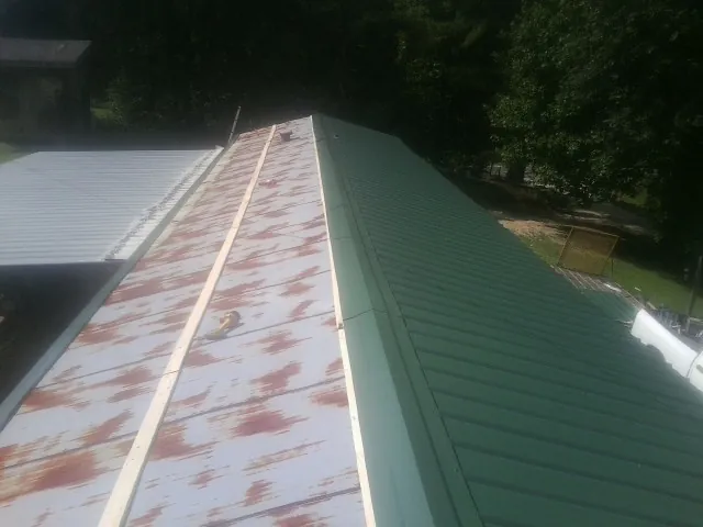 Old rusted panels beside newly installed green metal roofing — Wind Damage Roof Repair by Roofing Brothers in Ottawa Lake