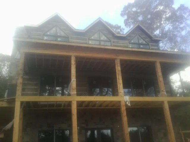 Dormers and porch framing on a large log home under construction — Roof Coating work by our crew in Ottawa Lake