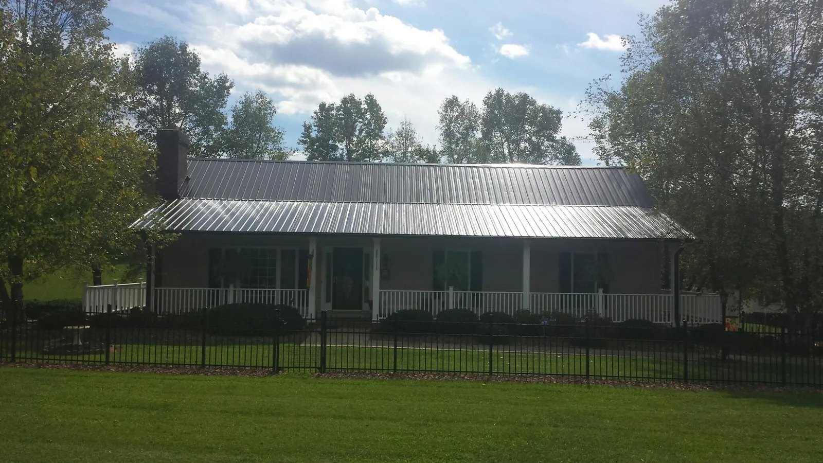 Gray metal roof on a brick ranch with a full width front porch — Gutter Guard Installation work by our crew in Ottawa Lake