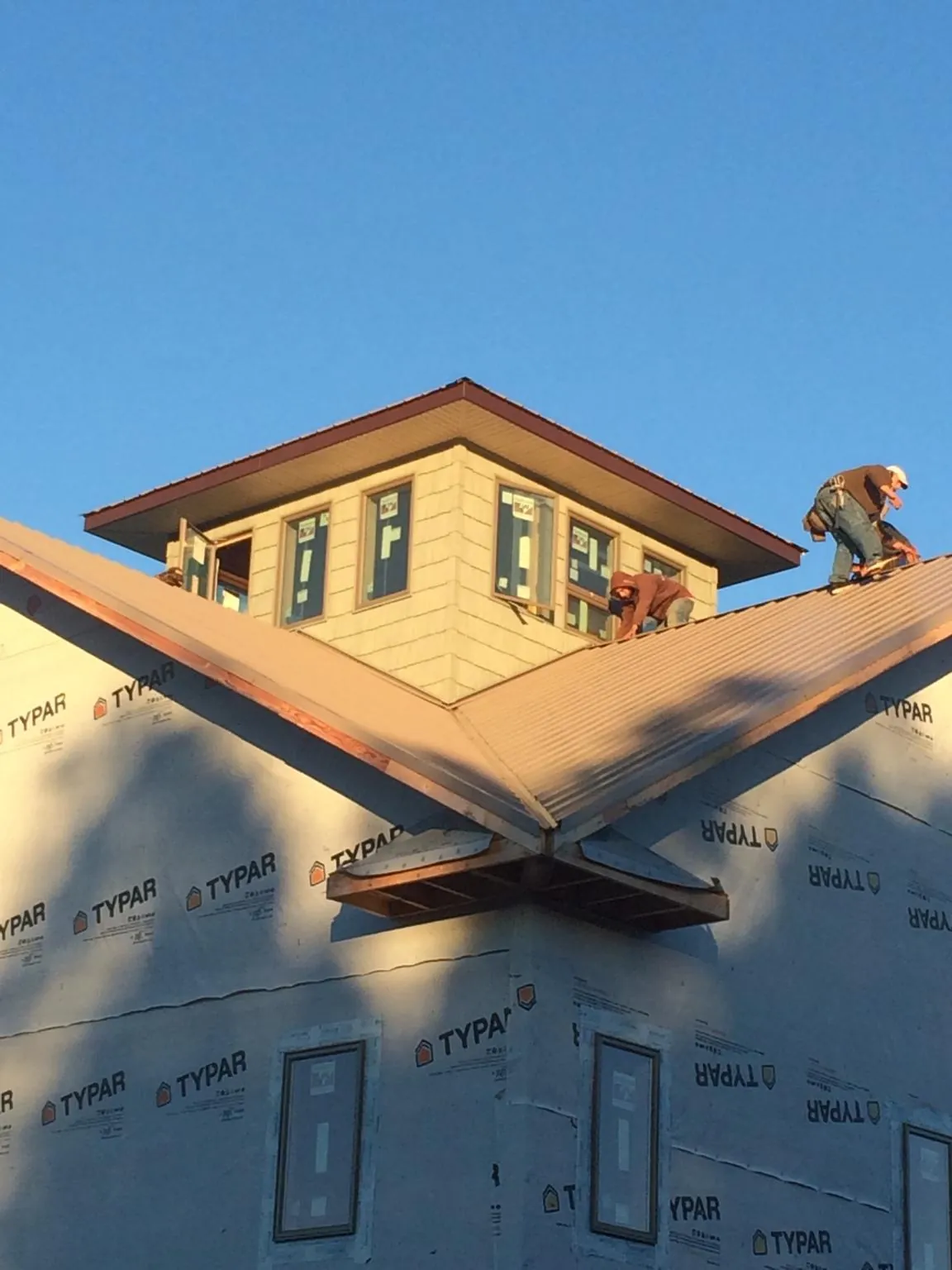 Roofers working around a rooftop cupola on a new metal roof at sunset — Roof Waterproofing in Ottawa Lake by Roofing Brothers